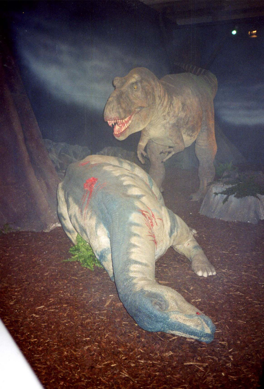 Foto eines Dioramas mit einem lebensgroßen T-Rex, der mit blutigem Gebiss vor einem soeben erlegten Beute-Saurier posiert.